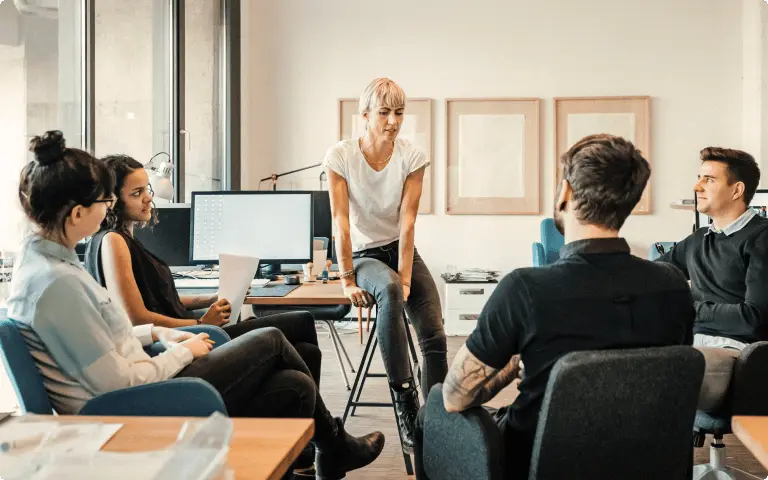 Cinco compañeros de trabajo reunidos en una oficina abierta