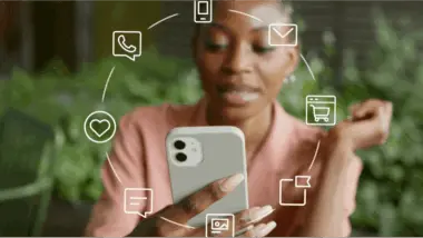 Femme utilisant un smartphone entourée d'icônes représentant des canaux de communication numériques, comme le téléphone et l'e-mail.