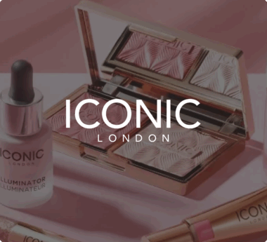 ICONIC London makeup products, including a highlighter palette and illuminator, displayed on a pink surface.