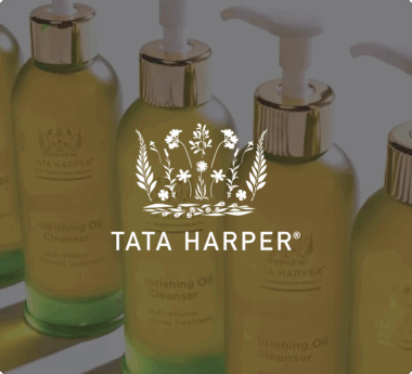 Tata Harper Nourishing Oil Cleanser bottles with pump dispensers and floral logo overlay.