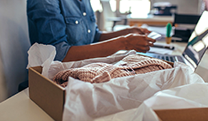 A box being packed with apparel by someone