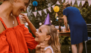 A woman and a child smiling with celebratory flags in the background