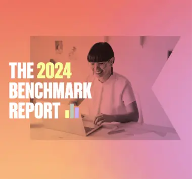 Bold white text reads "The 2024 Benchmark Report" on top of a photograph of a woman working at her computer.