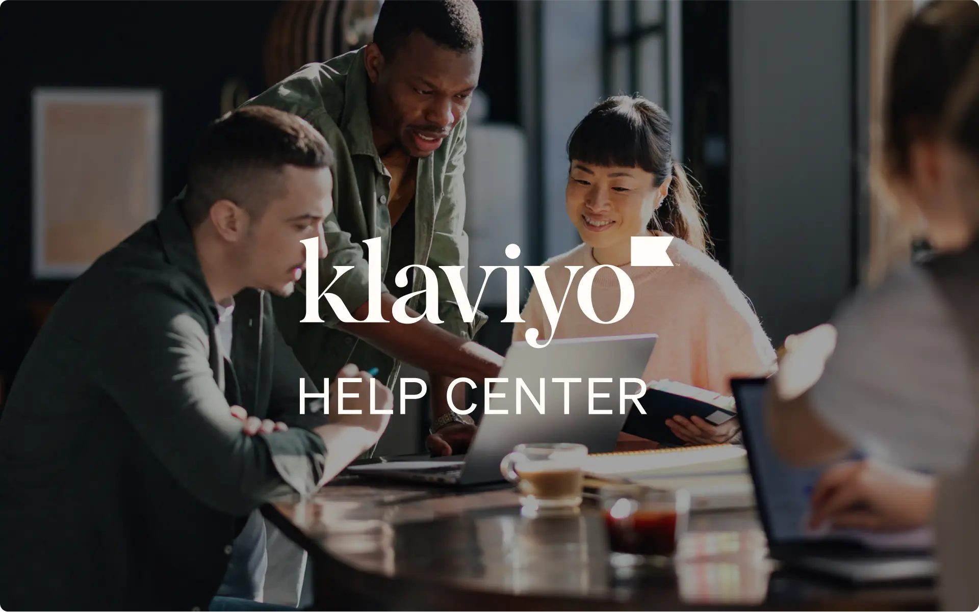 A diverse team collaborating at a coffee shop, with 'Klaviyo Help Center' text overlay, representing support and resources for Klaviyo users.