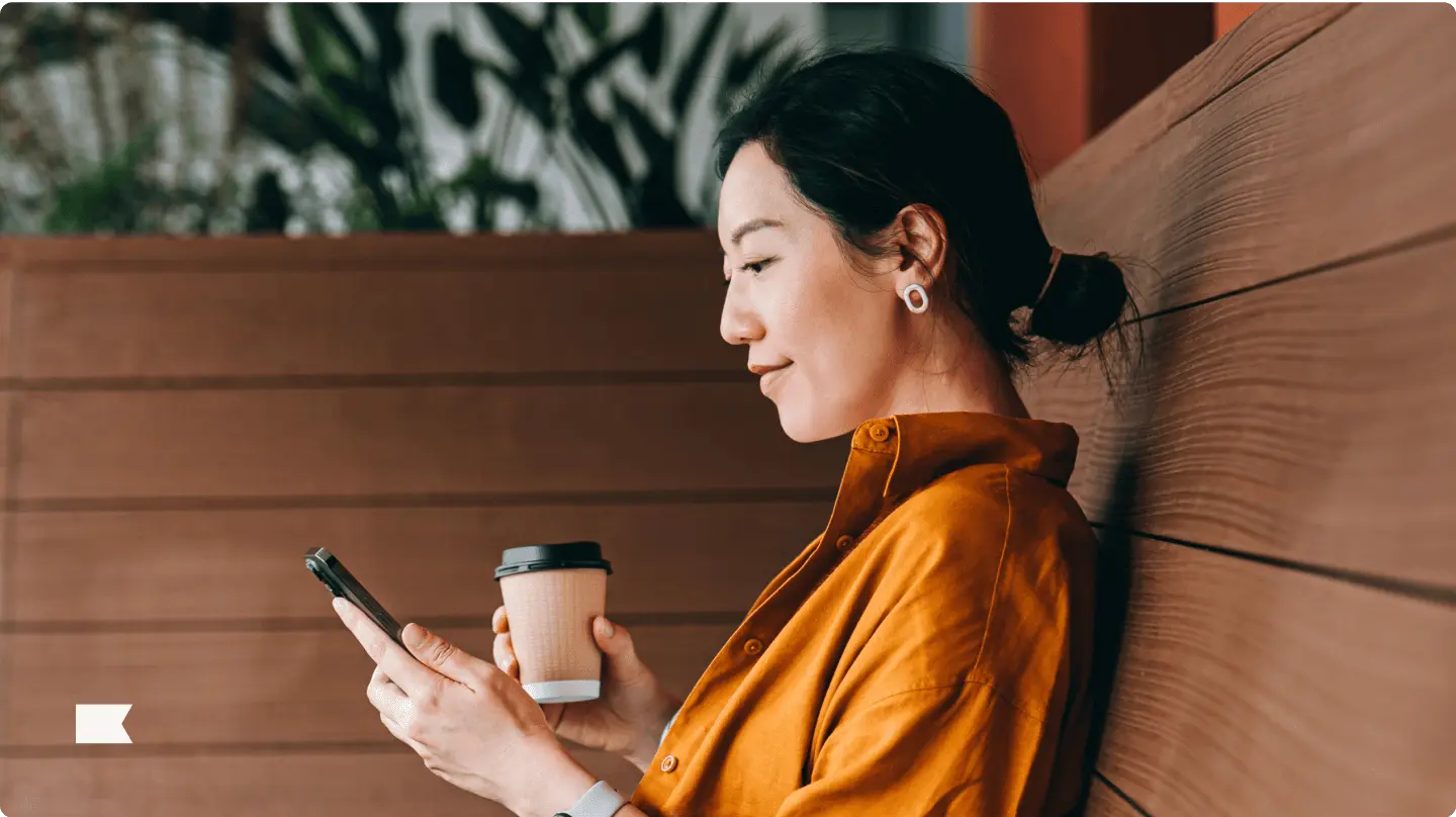 Person holding coffee and looking at phone