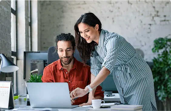 Photograph of 2 colleagues reviewing something on a laptop.