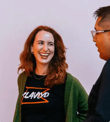Two people smiling and talking; one wears a "Klaviyo" shirt and green cardigan.